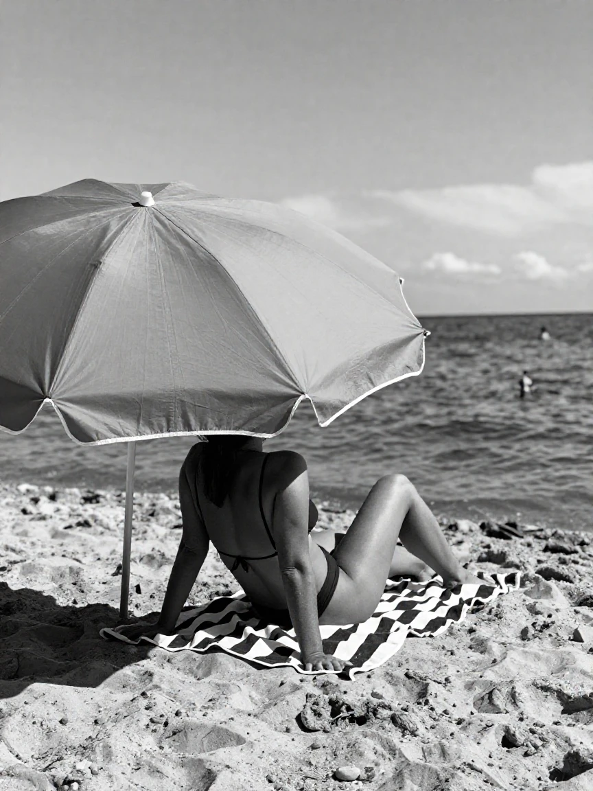 A sunbather relaxes beneath a colorful umbrella along a sun-drenched beach.