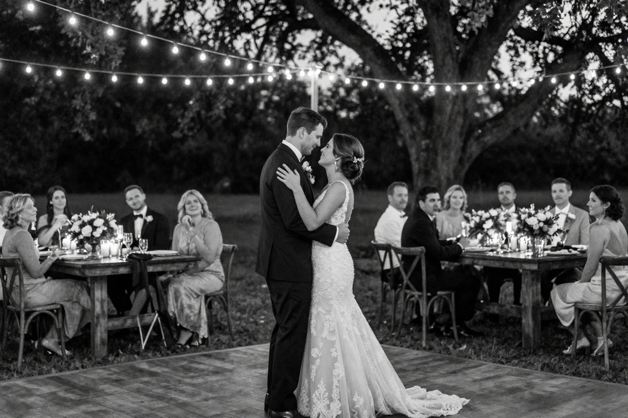 A groom and his bride share their first dance at an outdoor wedding reception.