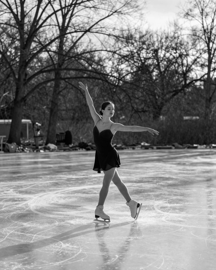 A figure skater spins gracefully across the ice on an outdoor frozen pond.