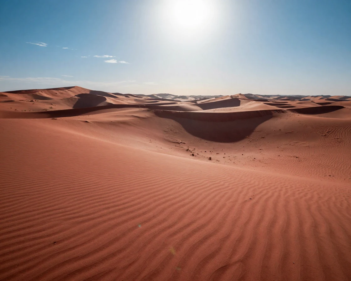 A vast desert of red sand dunes rippling under a blazing midday sun