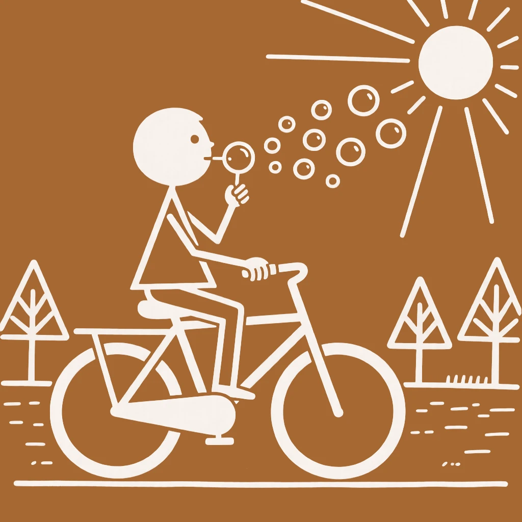 A young boy learning to ride a bicycle blowing soap bubbles in the afternoon sun.