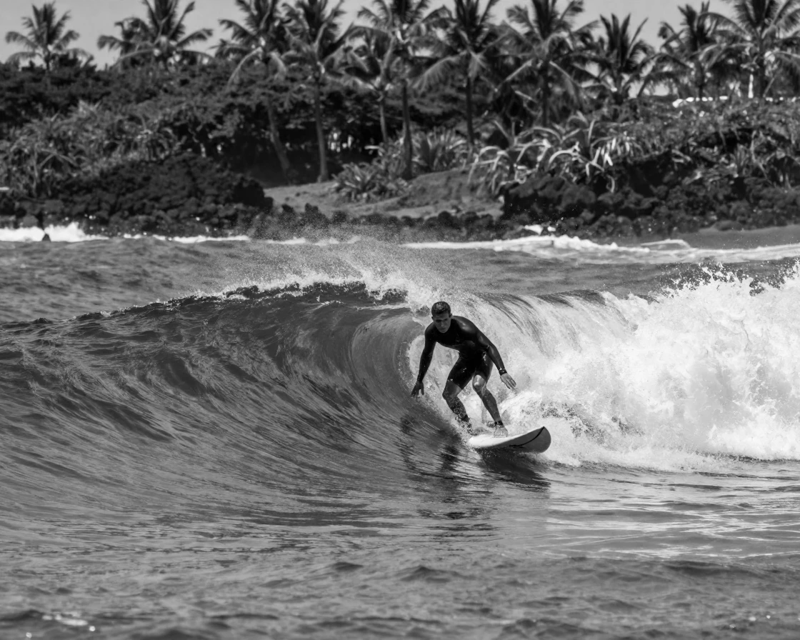 A surfer paddles into a curling ocean wave off a tropical coastline.