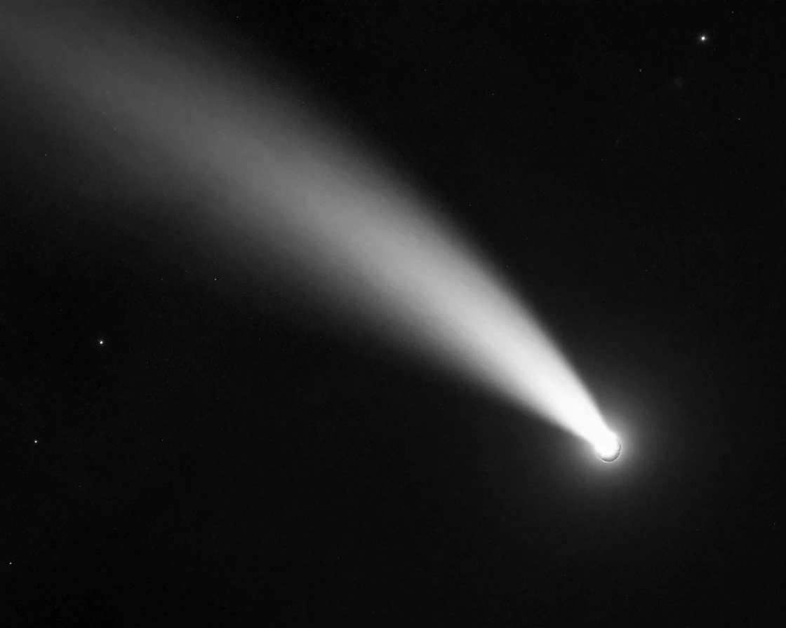 A comet streaks past with a glowing tail through the outer reaches of the solar system.